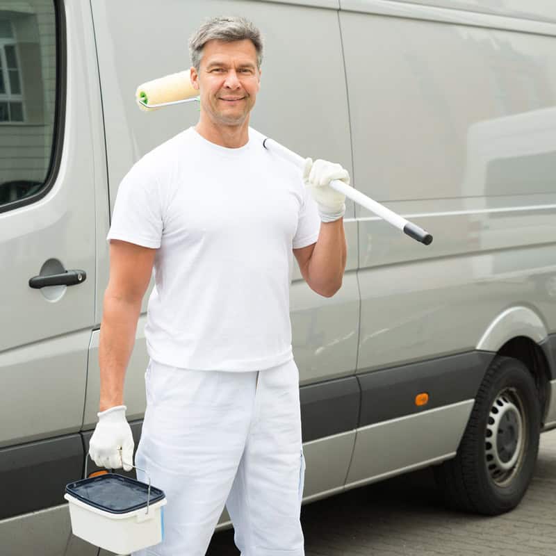 Maler steht mit seiner Ausrüstung vor einem transporter.