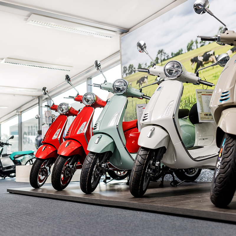 Eine Reihe bunter Vespa-Roller in der Ausstellung des Showrooms bei Kuhn+Witte.